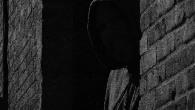 Stylized surveillance video of guy in a dark alley hiding from camera