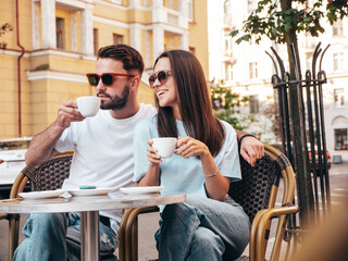 Smiling beautiful woman and her handsome boyfriend. Happy cheerful family. Couple drinking coffee in restaurant. They drinking tea at cafe in the street. Holding cup. Enjoying their date