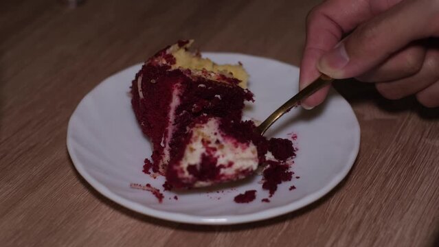 Video footage of a hand slicing red velvet cake on the small rounded plate
