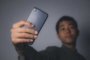 Young man using smartphone shooting selfie front camera.