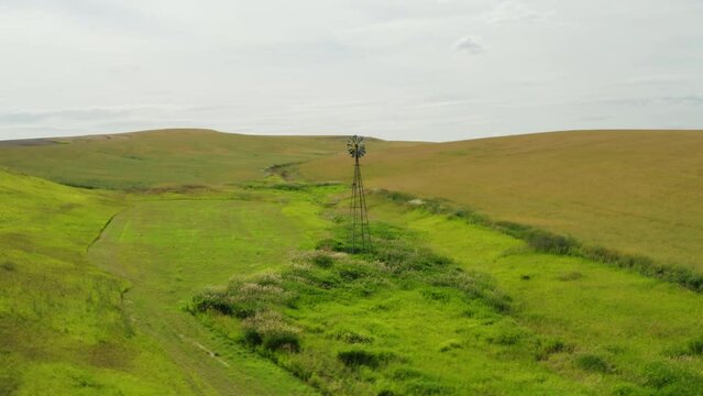 Old Aermotor windmill pump standing alone in small valley beside creek on ranch