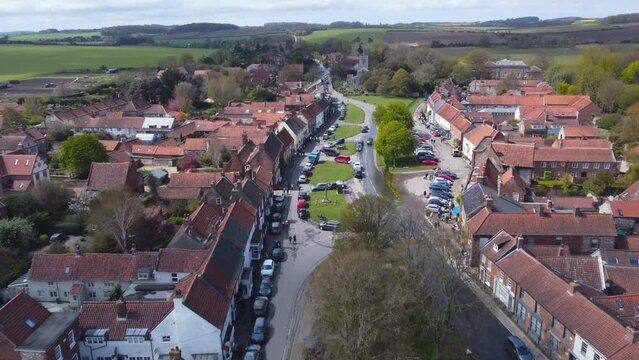 Aerial Drone Shot Flying Down Beautiful Old Village Burnham Market Main Street Towards St Mary's Church on Sunny and Cloudy Day in North Norfolk UK