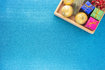 Christmas background in top view with copy space  and ornaments in wooden tray on blue glittering desktop.