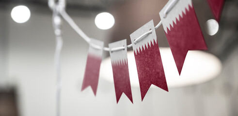 A garland of Qatar national flags on an abstract blurred background