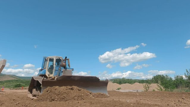 Earth movers leveling ground on road construction in field with dust