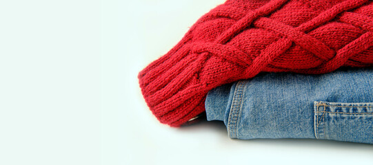 red wool knitted sweater sleeve and classic indigo jeans on white background, banner concept, copy space