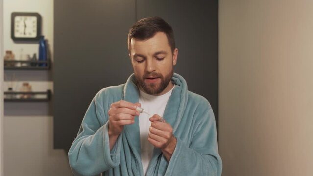Portrait of a young man taking care of his nails by applying oil