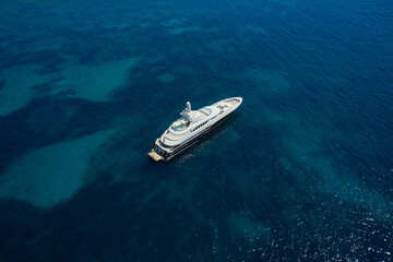 Big White Mega yacht is anchored on clear water, top view.