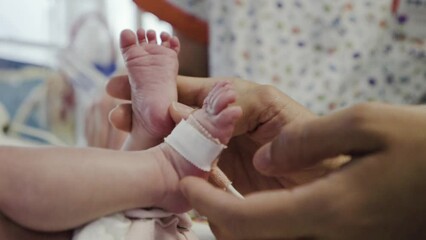 Close-up feet of a nursing baby who has recently been born. Newborn infant boy at hospital taking care 