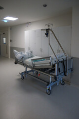 in a hospital corridor there is an empty bed