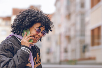 afro girl with sunglasses on the street talking on the mobile phone
