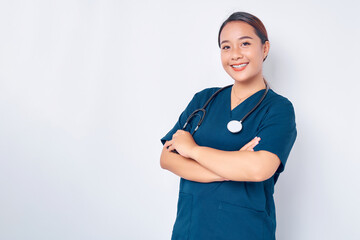 Smiling young Asian woman nurse wearing blue uniform with stethoscope cross arms chest and looking...