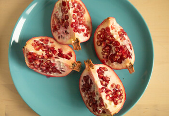 Halves of a pomegranate on a plate, on a light background. Weight loss, proper nutrition, diet,...