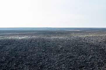 A plowed field in the early morning with fog starting to dissipate.