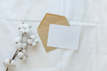 Postal envelope and a blank paper on a white sheet. Cotton branch and a letter with space for text