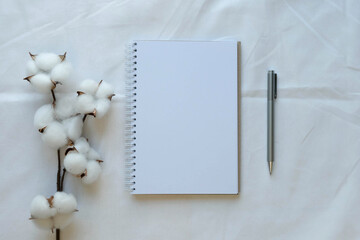 Blank note, pen and cotton branch on a white sheet. Composition with a place for a text