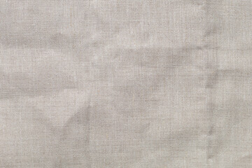 Fototapeta na wymiar Textured folds of linen fabric in natural beige color. Textile background, top view, copy space