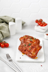 Cooked Marinated pork bbq ribs on ceramic white cutting board and white  grey background. Copy space, place for text.