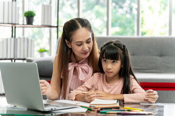 Asian family portrait, father and daughter in the living room The daughter did her homework with her mother, giving advice and teaching closely.