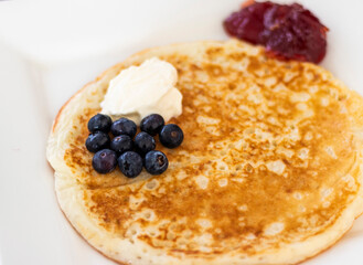 Close up shot of a pancake with sour cream and blueberries. Food