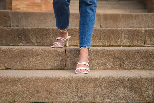 Woman Walking Down Stairs Wearing High Heels. You Can See Her Feet Going Down The Steps.