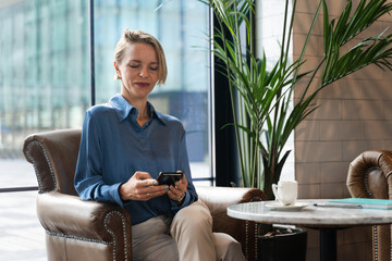 Blond Business woman using phone sitting in cafe. Successful inspired entrepreneur female having a...