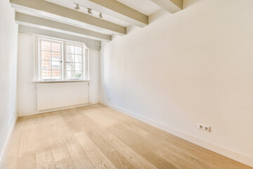 an empty room with white walls and wood flooring on one side, there is a small window in the corner