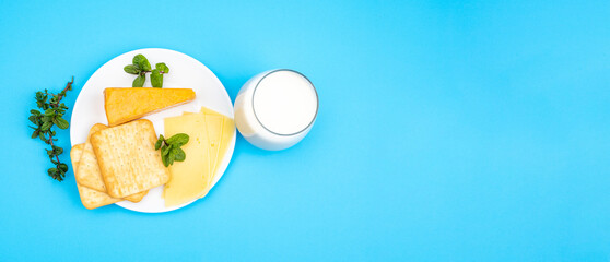 Varieties of homemade cheese, bread on a plate and a glass of milk. Blue background for holidays Shavuot, Pentecost.