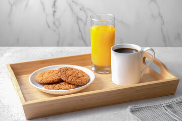 Lagom, Swedish concept of balanced lifestyle. Cozy morning with cup of coffee, vegan cookies, glass of orange juice on the wood tray on the stone background. Copy space.