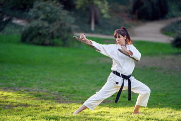 Karate fighter woman in kimono and black belt standing in karate pose while training outdoors. Sports and martial arts concept.