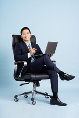 Asian businessman male portrait sitting on chair and isolated on blue background