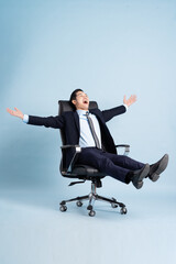 Asian businessman male portrait sitting on chair and isolated on blue background