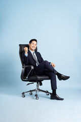 Asian businessman male portrait sitting on chair and isolated on blue background