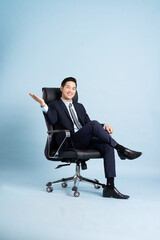 Asian businessman male portrait sitting on chair and isolated on blue background