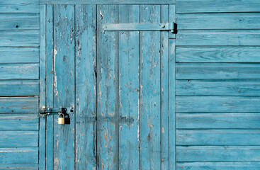 Old Wood texture Gate with Locked, Garage Door with Padlock, Rustic Blue Wooden wall with metal hinges,Barn entrance with sea blue peeling paint. Vintage concept background