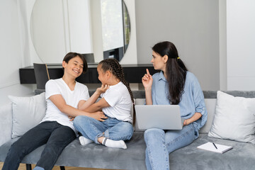Obraz premium Asian kids having fun while serious mother with laptop pointing with finger at home