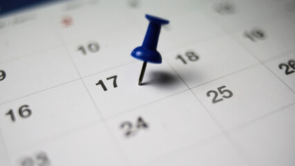 Embroidered blue pins on a calendar on the 25 th  with selective focus