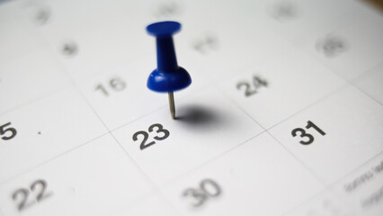 Embroidered blue pins on a calendar on the 23 th  with selective focus - Powered by Adobe