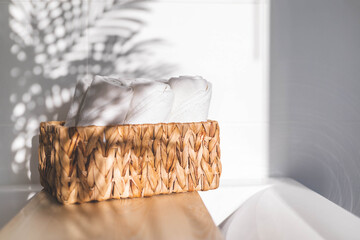 White bath towels rolled in woven jute basket on wooden shelf bathroom arrangement storage