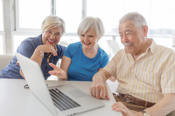 tre anziani fanno una videochiamata attraverso il computer portatile seduti in un bar  - obrazy, fototapety, plakaty