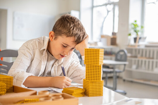 Smiling male kid with Montessori math golden bank material beads alternative counting development
