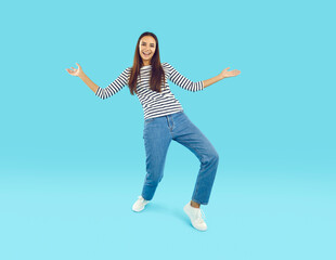 Full length photo of joyful attractive brunette young woman. Happy girl wearing striped longlsleeve and jeans standing opening arms hugging friendly against light blue background