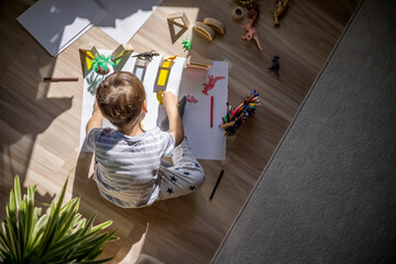 Male kid playing wooden bricks and dinosaurs drawing shadow on paper early development education