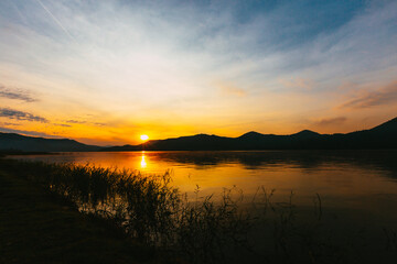 Sunrise time at lake or river with mountain on the background. in dark tone.