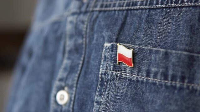 Metal badge with the flag of Poland is pinned on blue jeans jacket. Poland patriotism concept. Independence Day Holiday in Poland.