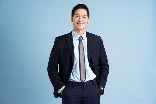 Portrait Of Asian Businessman Wearing Suit On Blue Background