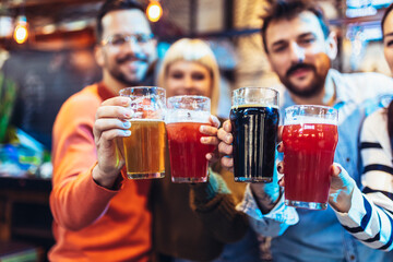 Smiling young friends drinking craft beer in pub