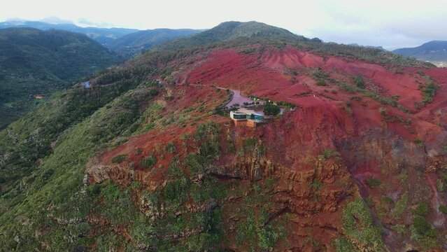 Aerial view of stunning viewpoint Mirador de Abrante with glass observation balcony above Agulo village in La Gomera island at sunrise. Restaurant on red clay.
