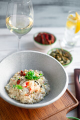 Risotto with crab meat and vegetables is served in a bowl. Dish with rice and seafood on table