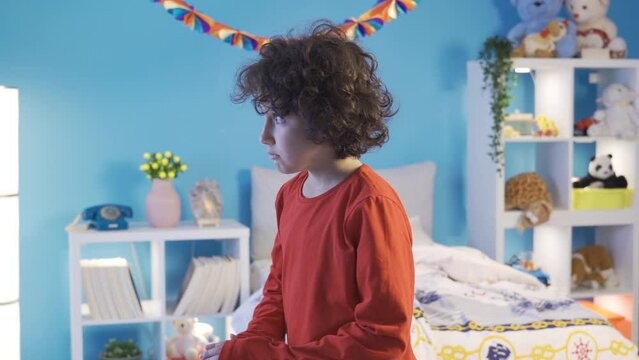 A boy is worried and scared when he sees scary shadows or objects in his bedroom at night.
Alone in his room, the boy is worried and afraid of the dark and scary things.
